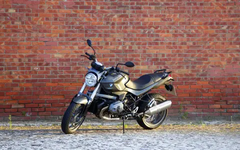 Szary motocykl BMW R1200R na tle ceglanej ściany. Poznaj jego dane techniczne i możliwości.