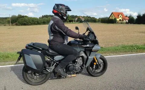 Motocyklista na Yamaha Tracer 900, z sakwami, w kasku, jedzie po drodze. Dane techniczne tego modelu są imponujące.