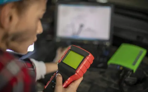 Mechanik z urządzeniem diagnostycznym i laptopem.