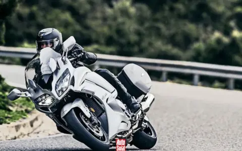 Motocyklista w białym Yamaha FJR 1300 na zakręcie drogi.