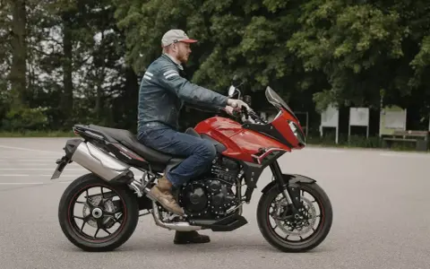 Mężczyzna na czerwonym motocyklu Triumph Tiger 1050. Poznaj jego dane techniczne i możliwości.