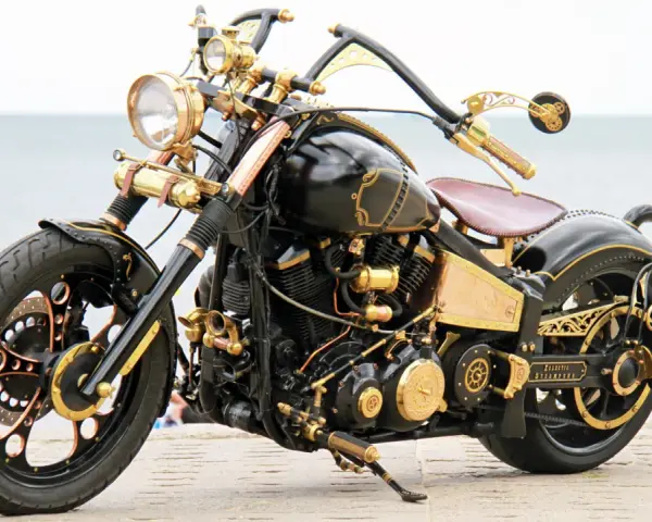Niestandardowy Yamaha Wild Star 1600 w stylu steampunk, z bogactwem złotych detali i mosiężnych elementów, prezentuje się imponująco nad morzem.