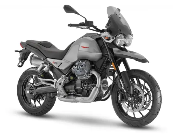 Srebrny motocykl Moto Guzzi V85 TT z czarnym siedzeniem i przyciemnianą szybą, gotowy na przygodę.