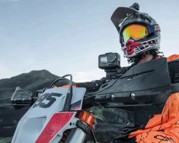 Motocyklista w kasku z kamerą na kierownicy, gotowy do jazdy po górskim terenie. Idealna kamera na kask motocyklowy do uchwycenia przygody.