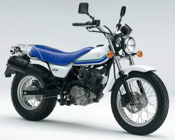 Biały Suzuki Van Van 125 z niebieskim siedzeniem i zielono-niebieskimi paskami na baku. Idealny na miejskie przygody.
