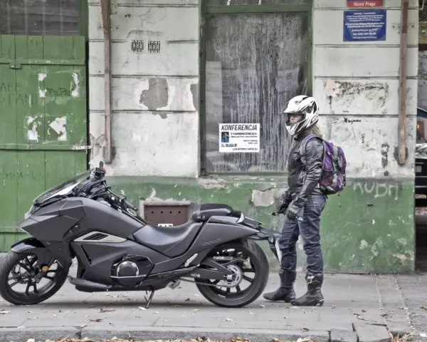 Motocyklista w kasku obok swojego futurystycznego Honda NM4 Vultus.