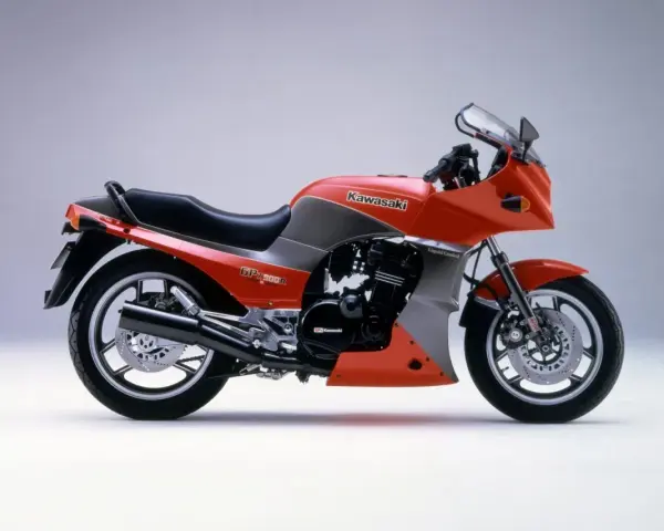 Pomarańczowy motocykl Kawasaki GPZ900R z szarymi akcentami, z lat 80., z owiewką i sportowym wyglądem.