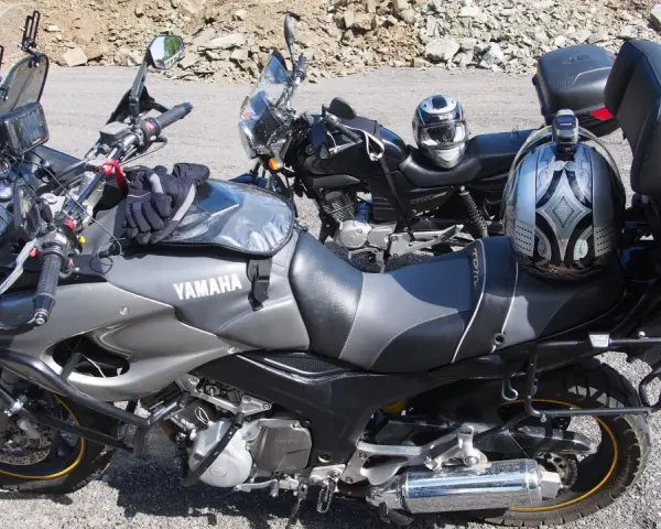 Dwa motocykle Yamaha zaparkowane na drodze szutrowej, jeden z kaskiem na siedzeniu.
