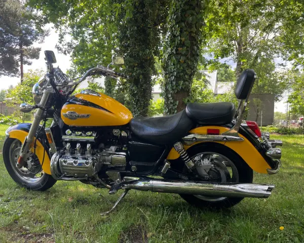 Żółta Honda Valkyrie 1500, z chromowanymi elementami i potężnym silnikiem, zaparkowana na trawie. Dane techniczne tego klasyka budzą podziw.