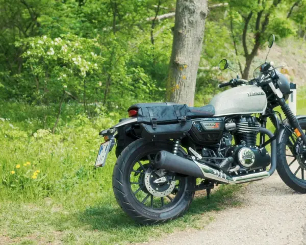 Stojący na poboczu, w otoczeniu zieleni, motocykl Honda GB350 z sakwami gotowy na podróż.