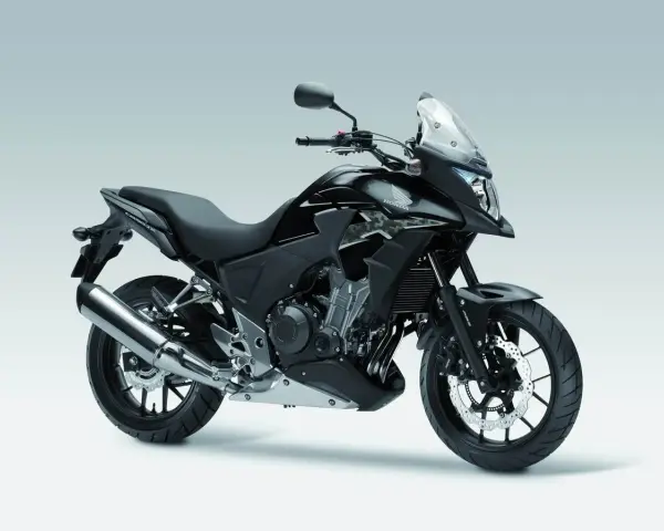 Czarny motocykl Honda CB500X z przyciemnianą szybą i srebrnym wydechem, gotowy na przygodę.