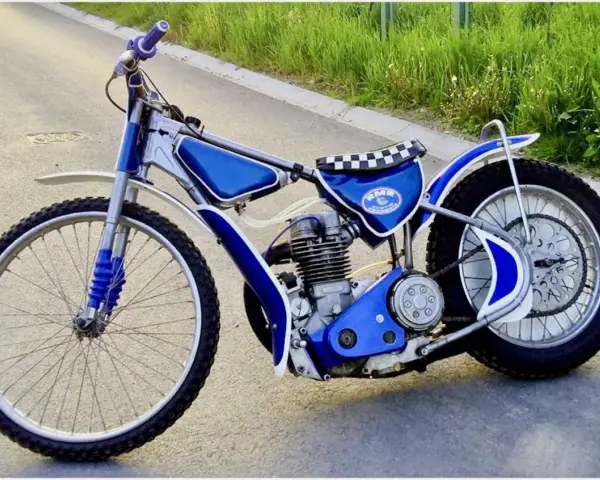 Niebieski motor żużlowy na asfalcie. Zastanawiasz się, ile kosztuje motor żużlowy? Ten wygląda na gotowy do startu!