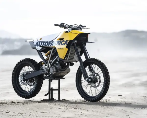 Żółto-biały motocykl customowy Autofabrica Type 17, bazujący na BMW G450X, stoi na plaży.