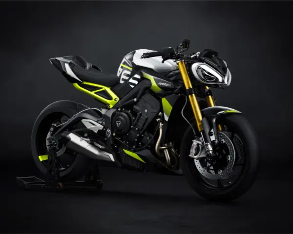 Agresywny Triumph Street Triple w biało-czarnej kolorystyce z neonowo-żółtymi akcentami, zdominowany przez złote lagi i sportowy wygląd.