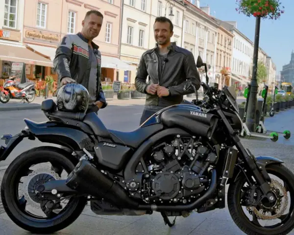 Dwóch mężczyzn pozuje obok czarnego motocykla Yamaha V-Max 1700 na ulicy.