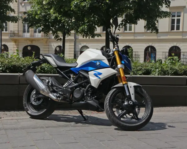 Biało-niebieski motocykl BMW G 310 R na tle kamienicy. Sprawdź jego dane techniczne!