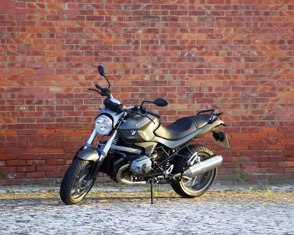 Szary motocykl BMW R1200R na tle ceglanej ściany. Poznaj jego dane techniczne i możliwości.