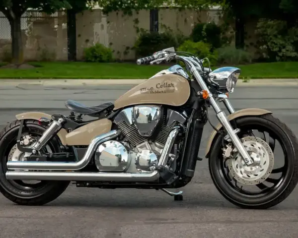 Beżowy motocykl Honda VTX 1300 z chromowanymi elementami i czarnym siedzeniem, zaparkowany na ulicy.