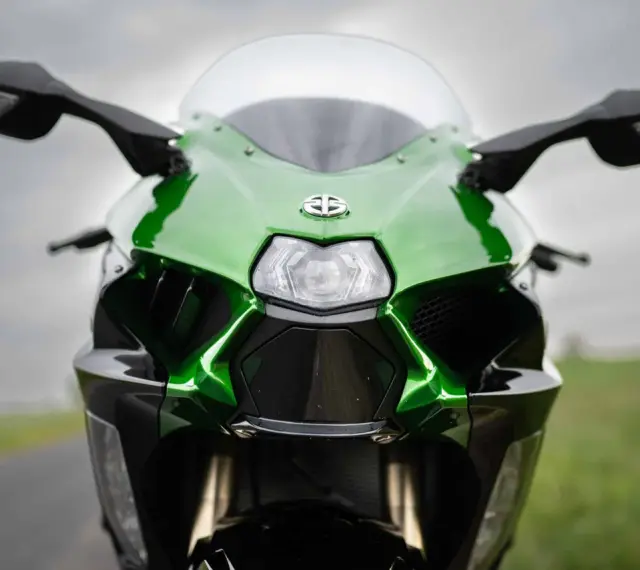 Przód zielono-czarnego motocykla Kawasaki Ninja H2 z błyszczącym logo i ostrymi liniami, gotowy do jazdy.