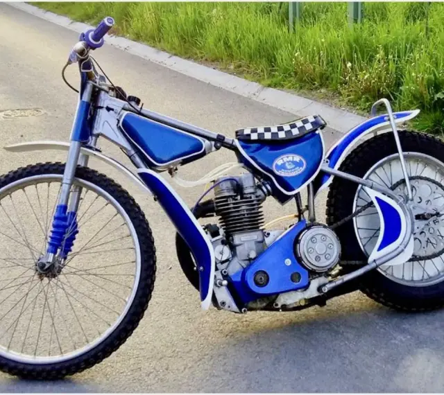Niebieski motor żużlowy na asfalcie. Zastanawiasz się, ile kosztuje motor żużlowy? Ten wygląda na gotowy do startu!