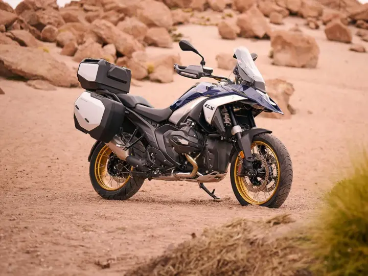 Nowy motocykl BMW R1300GS z kuframi, gotowy na przygodę po pustynnych terenach.