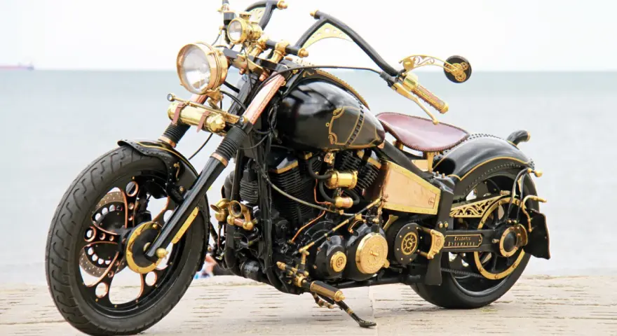 Niestandardowy Yamaha Wild Star 1600 w stylu steampunk, z bogactwem złotych detali i mosiężnych elementów, prezentuje się imponująco nad morzem.
