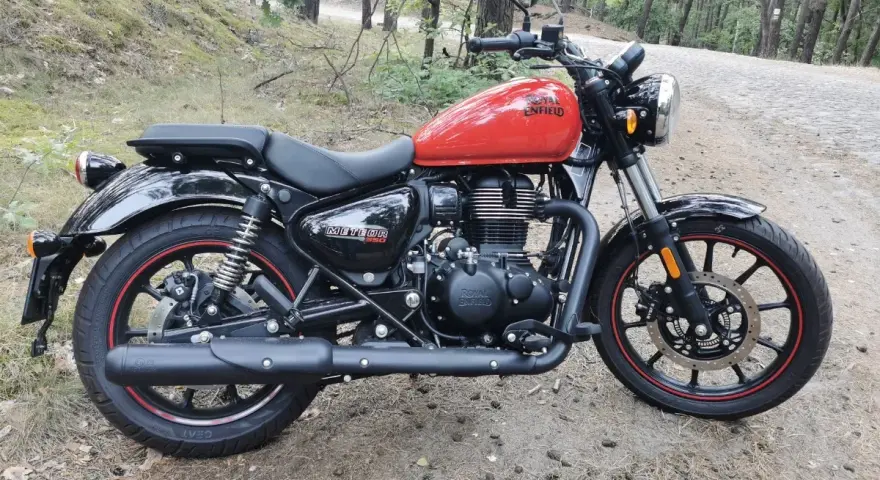 Czerwony Royal Enfield Meteor 350 na leśnej drodze. Klasyczny wygląd i nowoczesna technologia w jednym.