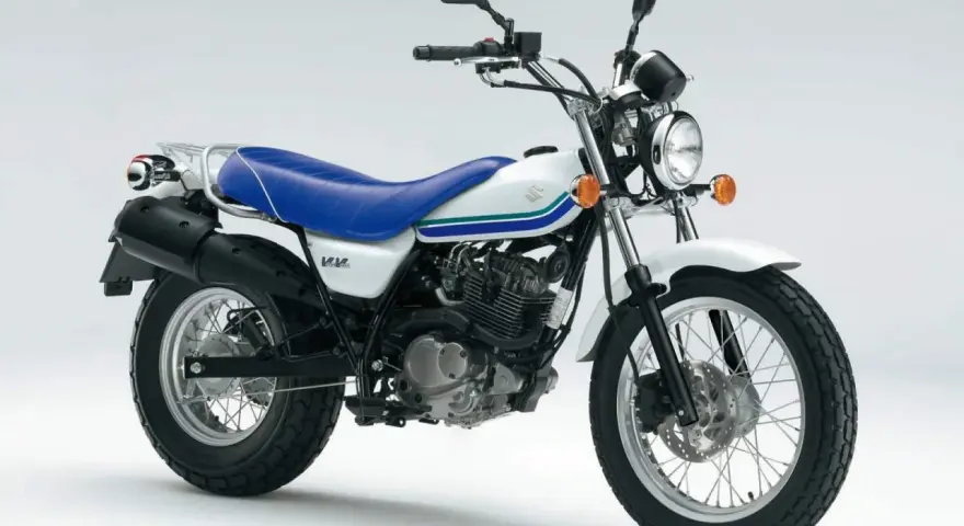 Biały Suzuki Van Van 125 z niebieskim siedzeniem i zielono-niebieskimi paskami na baku. Idealny na miejskie przygody.