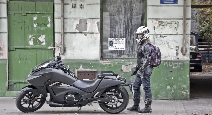 Motocyklista w kasku obok swojego futurystycznego Honda NM4 Vultus.