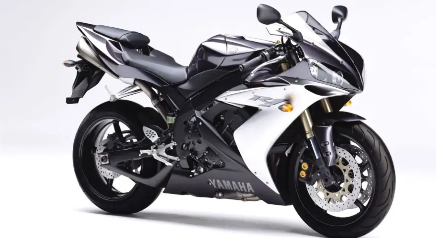 Sportowy motocykl Yamaha R1, jedna z wielu generacji, w kolorze czarno-białym, prezentuje się dynamicznie na białym tle.