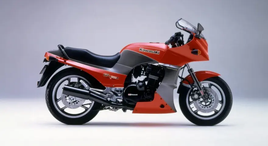Pomarańczowy motocykl Kawasaki GPZ900R z szarymi akcentami, z lat 80., z owiewką i sportowym wyglądem.