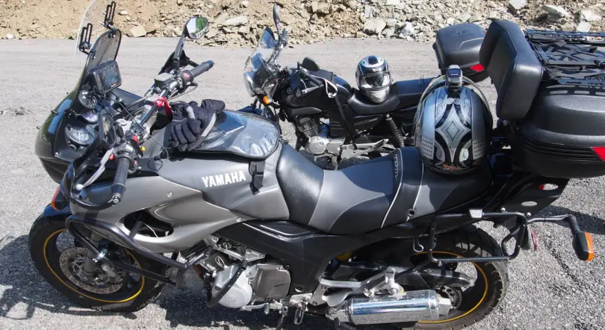 Dwa motocykle Yamaha zaparkowane na drodze szutrowej, jeden z kaskiem na siedzeniu.