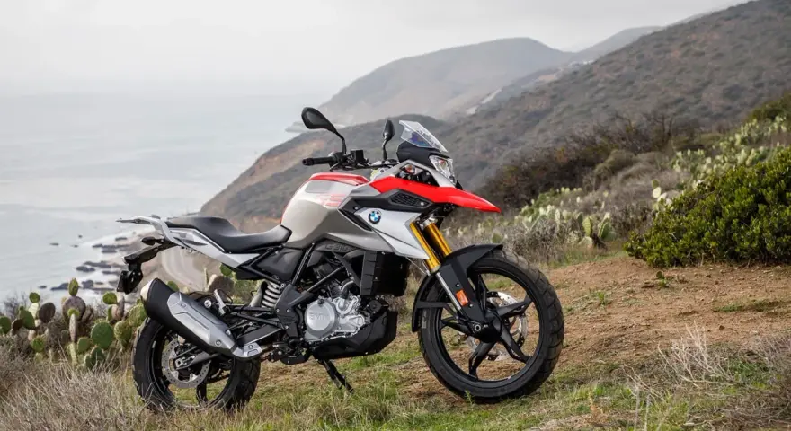 BMW G 310 GS na tle górskiego krajobrazu z widokiem na ocean. Poznaj jego dane techniczne i możliwości terenowe.