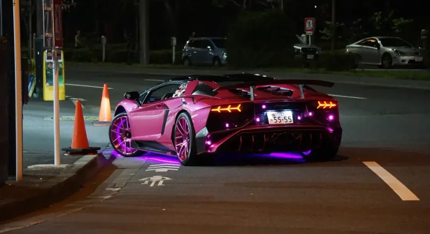 Różowy Lamborghini z neonowym podświetleniem na ulicy nocą.
