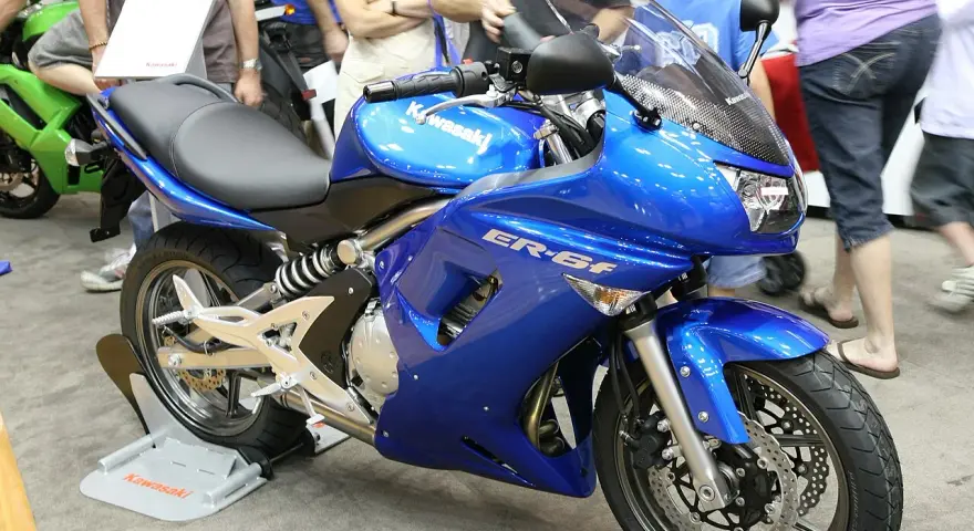 Błękitny motocykl Kawasaki ER-6f, z widocznymi danymi technicznymi na owiewce, prezentowany na wystawie.