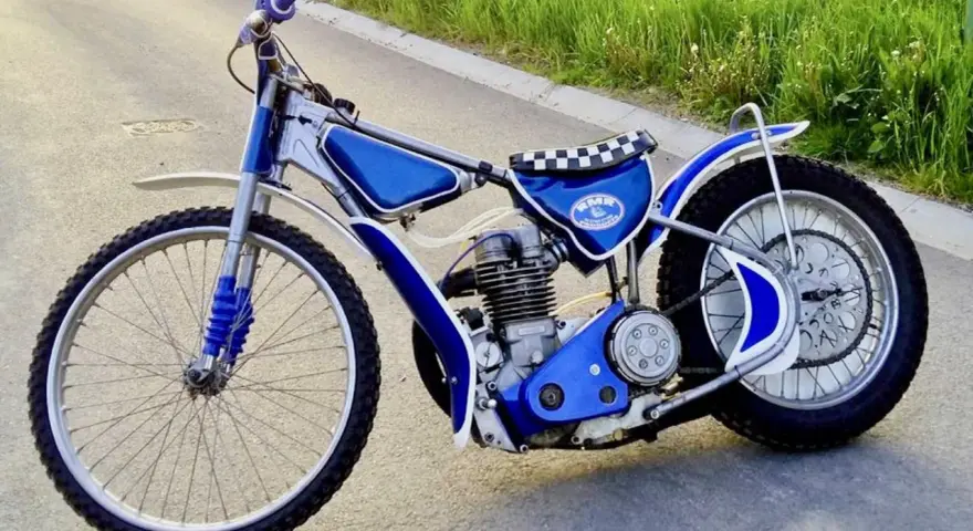 Niebieski motor żużlowy na asfalcie. Zastanawiasz się, ile kosztuje motor żużlowy? Ten wygląda na gotowy do startu!