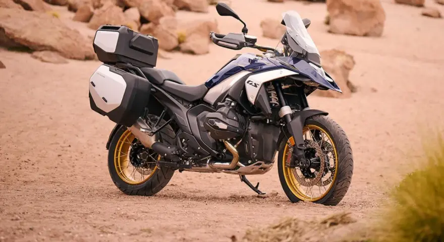 Nowy motocykl BMW R1300GS z kuframi, gotowy na przygodę po pustynnych terenach.
