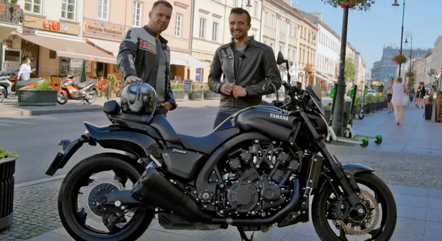 Dwóch mężczyzn pozuje obok czarnego motocykla Yamaha V-Max 1700 na ulicy.
