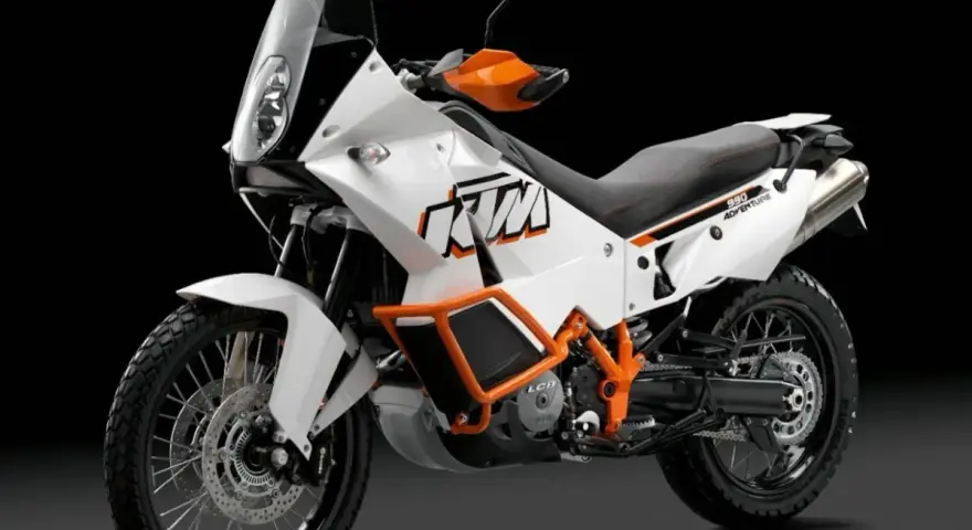 Biały motocykl KTM 990 Adventure z pomarańczowymi akcentami, gotowy na każdą przygodę.