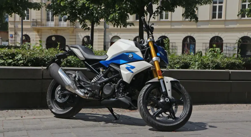 Biało-niebieski motocykl BMW G 310 R na tle kamienicy. Sprawdź jego dane techniczne!