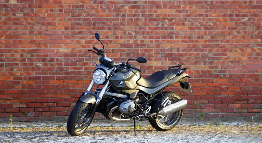 Szary motocykl BMW R1200R na tle ceglanej ściany. Poznaj jego dane techniczne i możliwości.