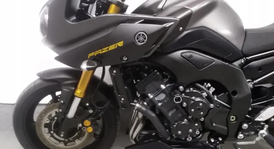 Ciemnoszary motocykl Yamaha FZ8 z żółtym napisem "FAZER" na owiewce. Widoczny silnik i przednie zawieszenie.