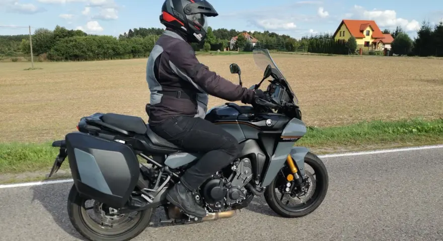 Motocyklista na Yamaha Tracer 900, z sakwami, w kasku, jedzie po drodze. Dane techniczne tego modelu są imponujące.