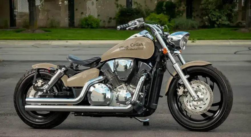 Beżowy motocykl Honda VTX 1300 z chromowanymi elementami i czarnym siedzeniem, zaparkowany na ulicy.