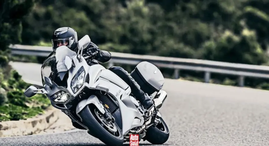 Motocyklista w białym Yamaha FJR 1300 na zakręcie drogi.