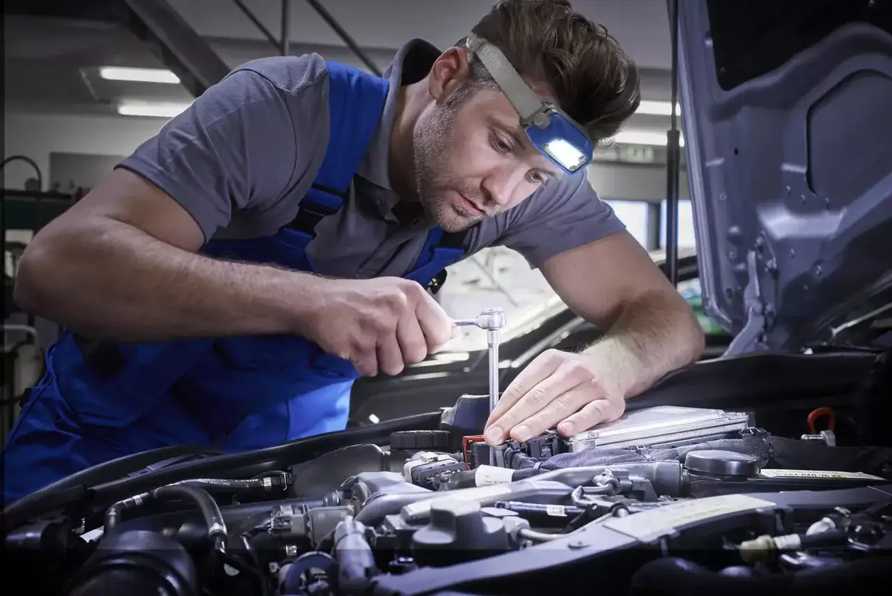 mechanik z latarką czołową w warsztacie samochodowym