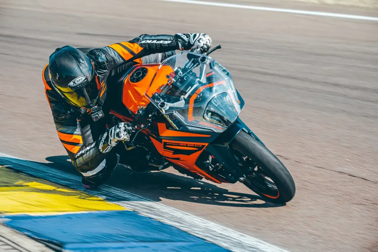 Motocyklista pochyla się na torze na pomarańczowo-czarnym KTM RC 390. Dane techniczne tego sportowego motocykla pozwalają na takie manewry.