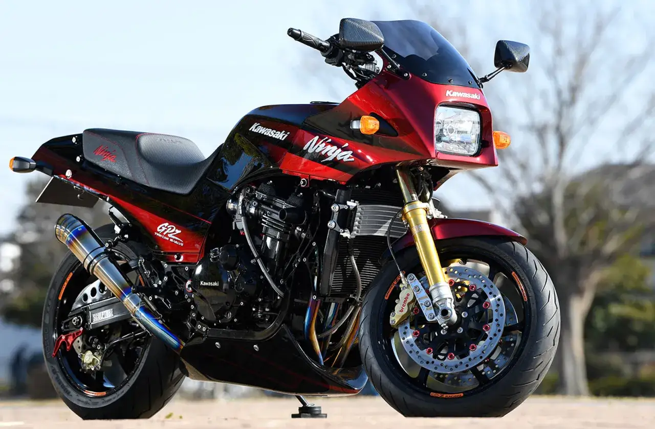 Błyszczący, czerwono-czarny motocykl Kawasaki GPZ900R Ninja z wydechem Yoshimura i złotym zawieszeniem.