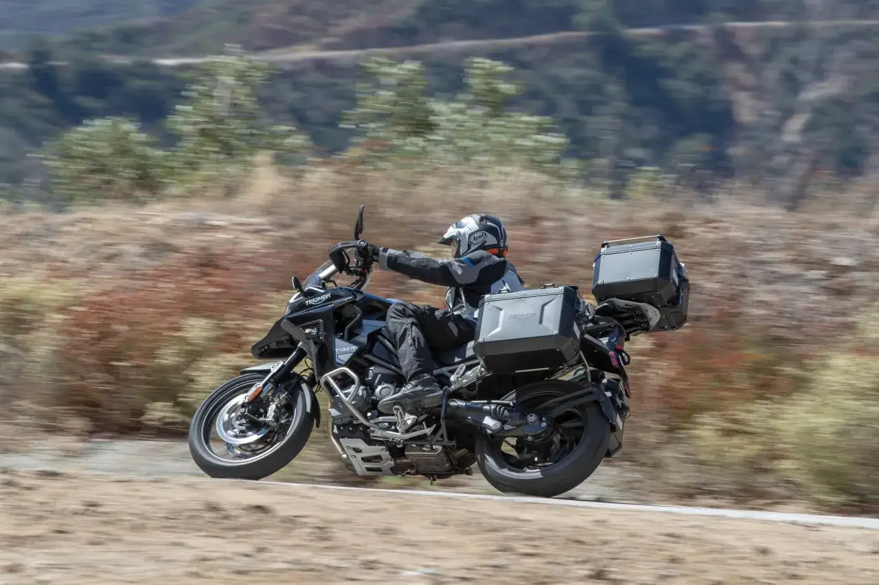 Motocyklista na Triumph Tiger 1200 pokonuje zakręt na górskiej drodze. Poznaj jego dane techniczne!