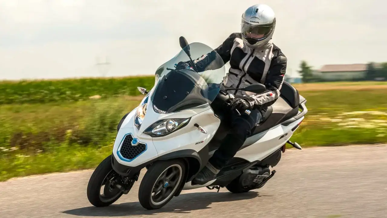 Jazda Piaggio MP3 500 po wiejskiej drodze, testując jego prędkość maksymalną.
